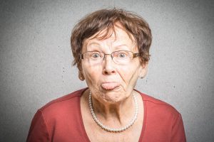 An elderly woman playfully sticking out her tongue, symbolizing the enduring power and relevance of radio in the media landscape.